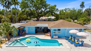 A residential property with a swimming pool, outdoor seating, and a garage. - Sleeps 10 Pickleball Pool Tiki Bar Games (Bradenton)