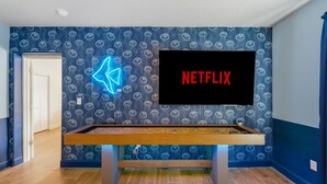 A room with a pool table, a neon sign, and a TV screen displaying 'NETFLIX'. - Sleeps 10 Pickleball Pool Tiki Bar Games (Bradenton)