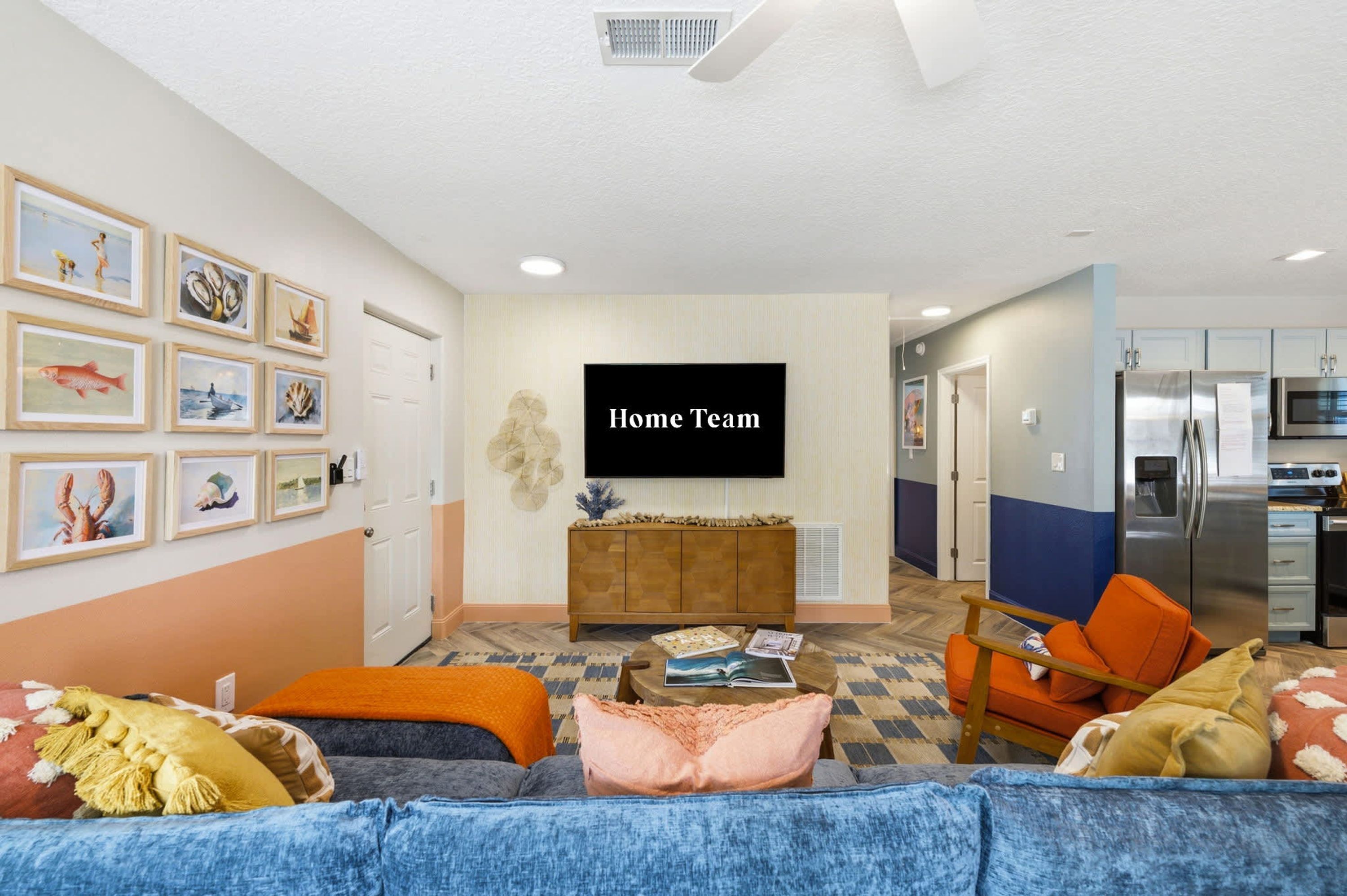 A living room with a flat-screen TV, a sofa, a coffee table, and a kitchen area with a refrigerator and microwave.