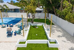 A backyard with a swimming pool, green lawn, and outdoor seating area. - Sleeps 10 Pickleball Pool Tiki Bar Games (Bradenton)