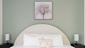 Ein Schlafzimmer mit einem großen Bett, zwei Nachttischen und einem gerahmten Bild an der Wand.