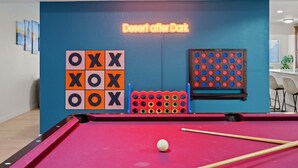 Ein Billardtisch mit einem Neon-Schild, das 'Desert after Dark' zeigt, und einem vorbereiteten Tic-Tac-Toe-Spiel.