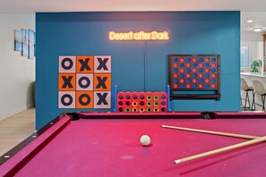 Ein Billardtisch mit einem Neon-Schild, das 'Desert after Dark' zeigt, und einem vorbereiteten Tic-Tac-Toe-Spiel.