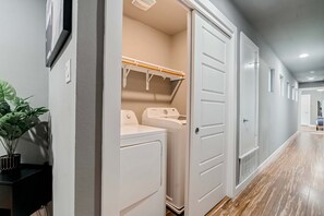 A laundry room with a washing machine and dryer, a drying rack, and a potted plant. - The Rosewood Retreat 6BR s Hottub Dogfriendly (Austin)
