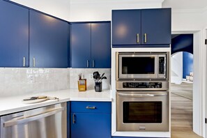Eine moderne Küche mit blauen Schränken, einem Edelstahl-Geschirrspüler, einer Mikrowelle und einem eingebauten Backofen.