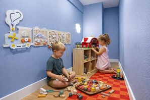 Ein Kind spielt mit Spielzeug in einem Zimmer mit blauen Wänden und Holzboden.
