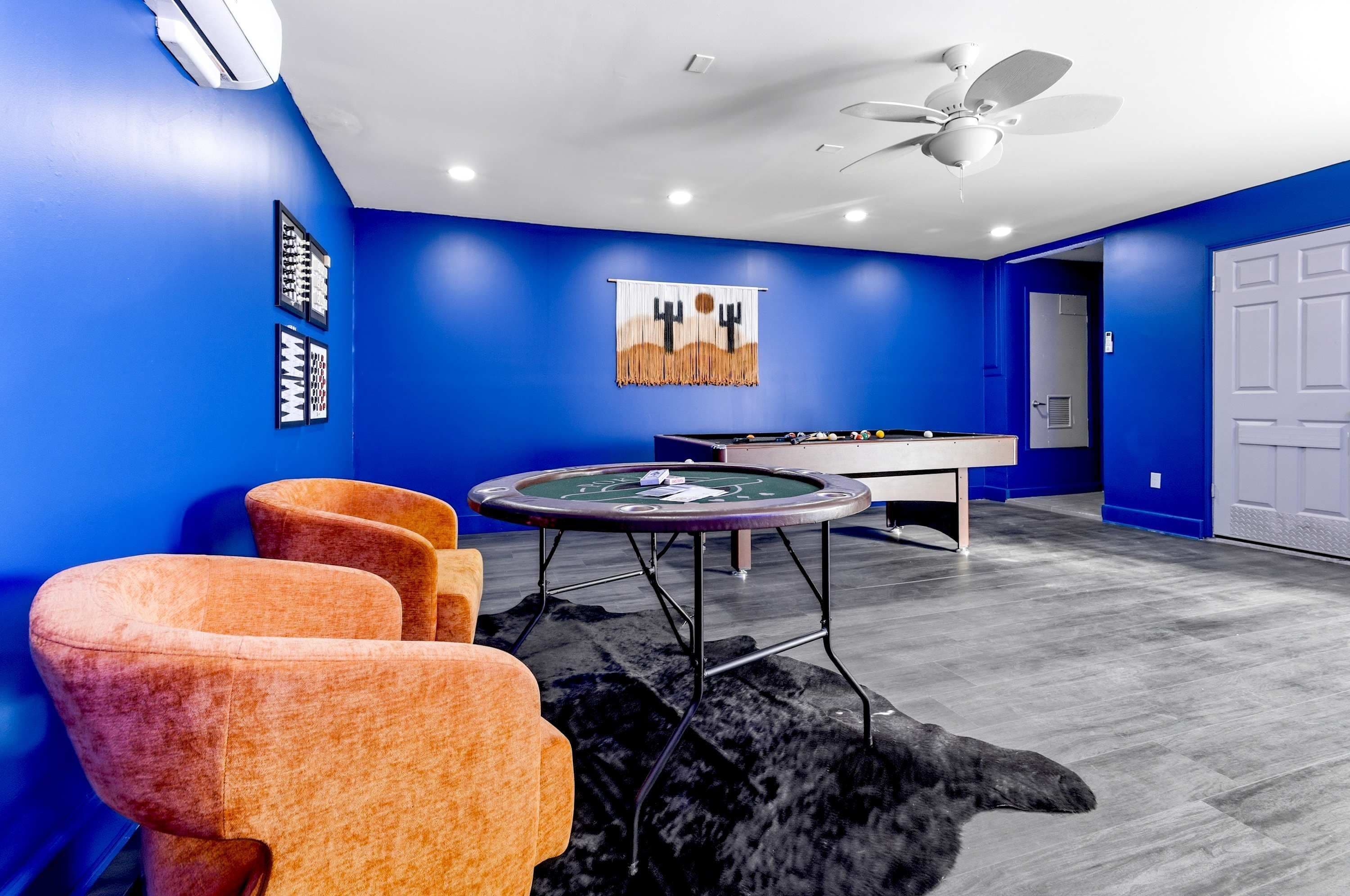 A room with blue walls, a ceiling fan, a pool table, and a billiards setup.