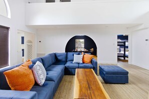 Ein modernes Wohnzimmer mit Ecksofa, Hocker und Couchtisch aus Holz.