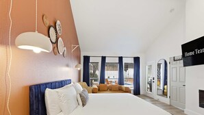 Ett hotellrum med en stor säng, en soffa, en matplats och en TV.