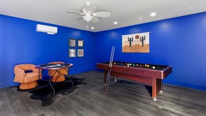Ett rum med blå väggar, ett biljardbord, ett bordtennisbord och en takfläkt.