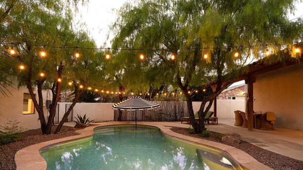 A swimming pool surrounded by trees, string lights, and outdoor furniture. - The Tucson Bungalow Sam Hughes Pueblo (Tucson)