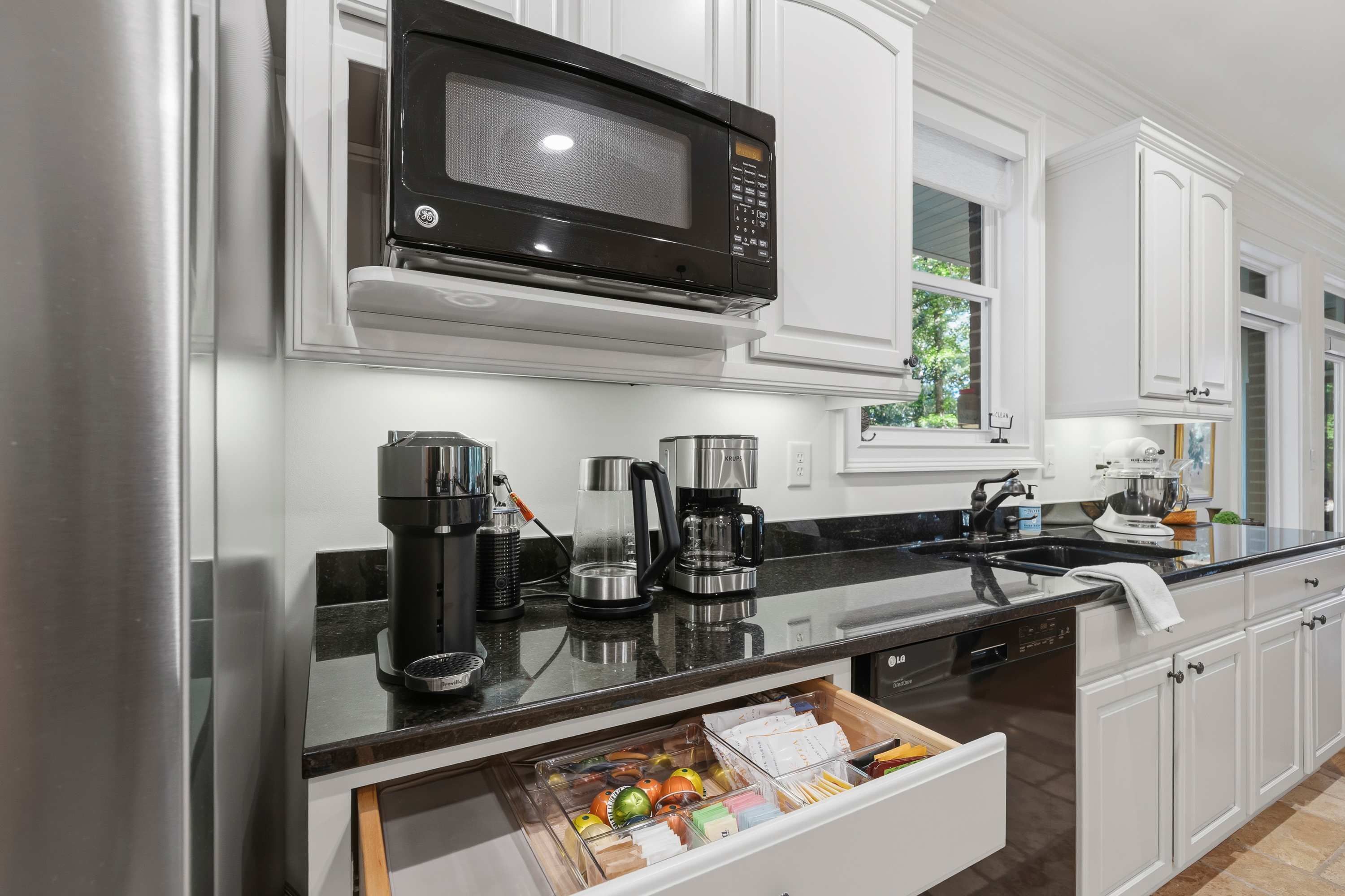 A modern kitchen with a built-in microwave, coffee maker, and a drawer organizer.