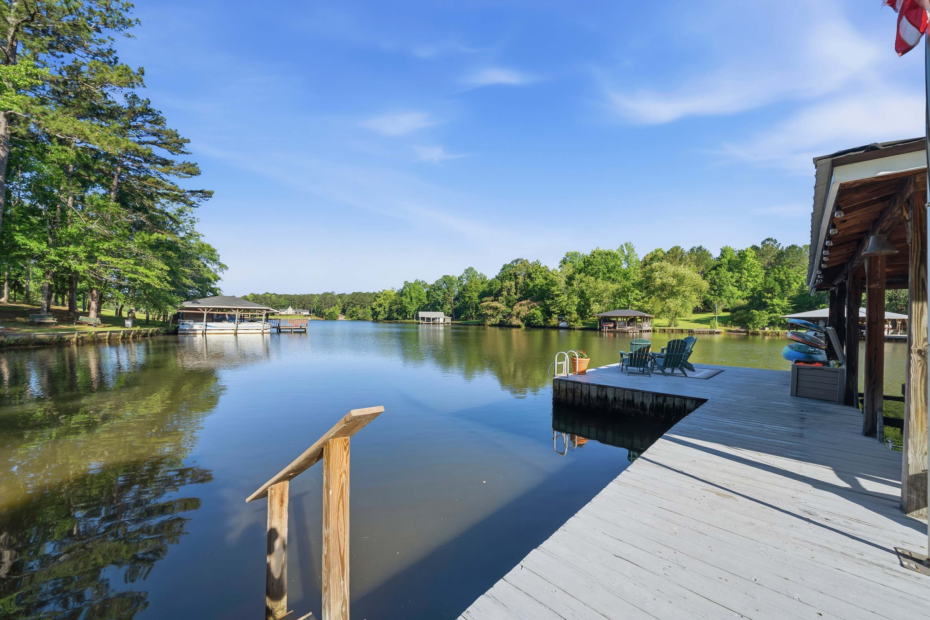 A calm lake with a dock, boats, and a building with outdoor seating.