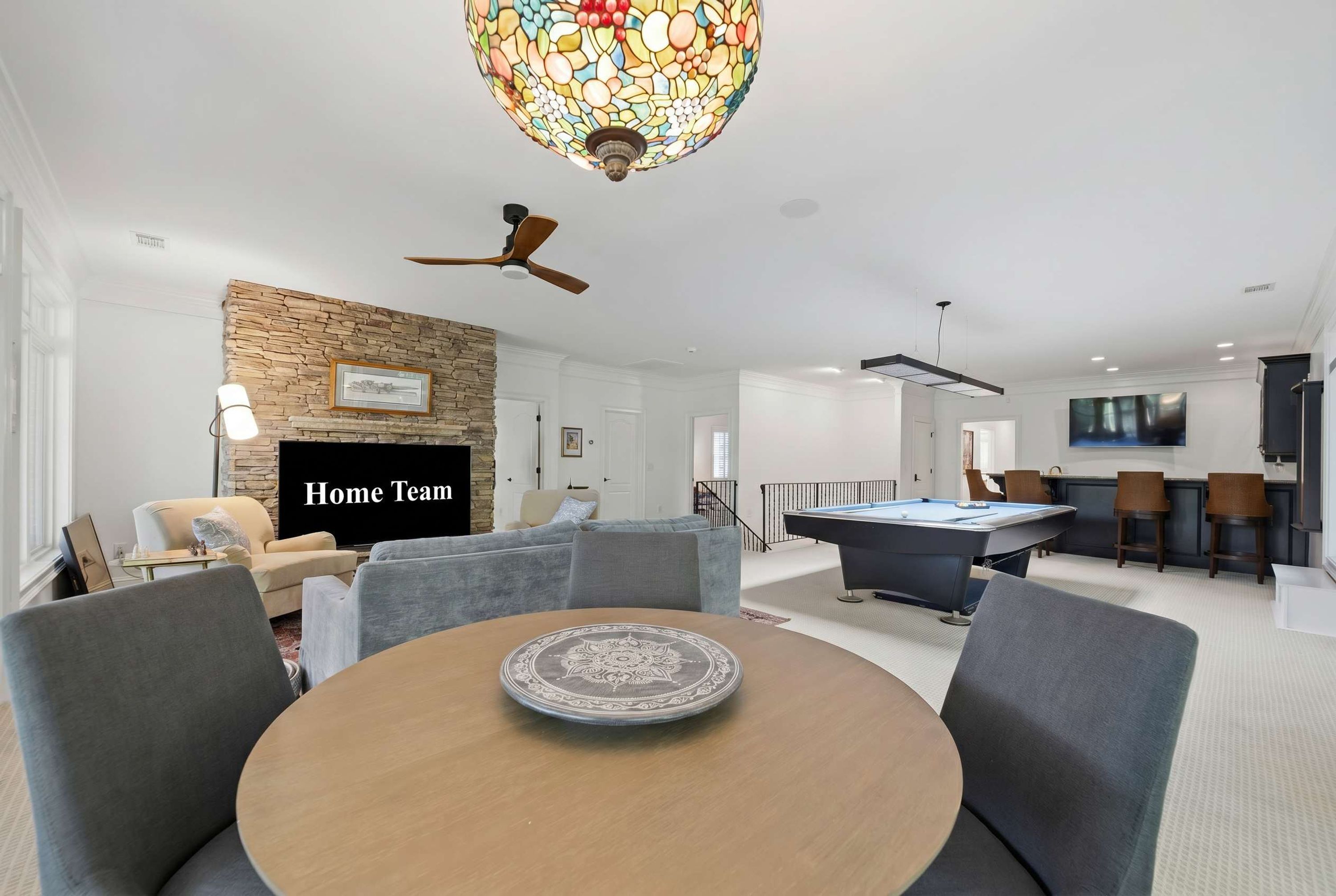 A modern living room with a fireplace, a pool table, and a television.