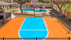 Un terrain de basket avec une piscine en arrière-plan.
