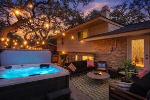 Ein Whirlpool mit Steinfassade, eine Steinsäule, eine Couch und ein gemustertes Teppich.