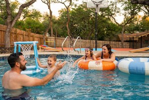 Une piscine équipée d’un panier de basketball et de jeux gonflables.