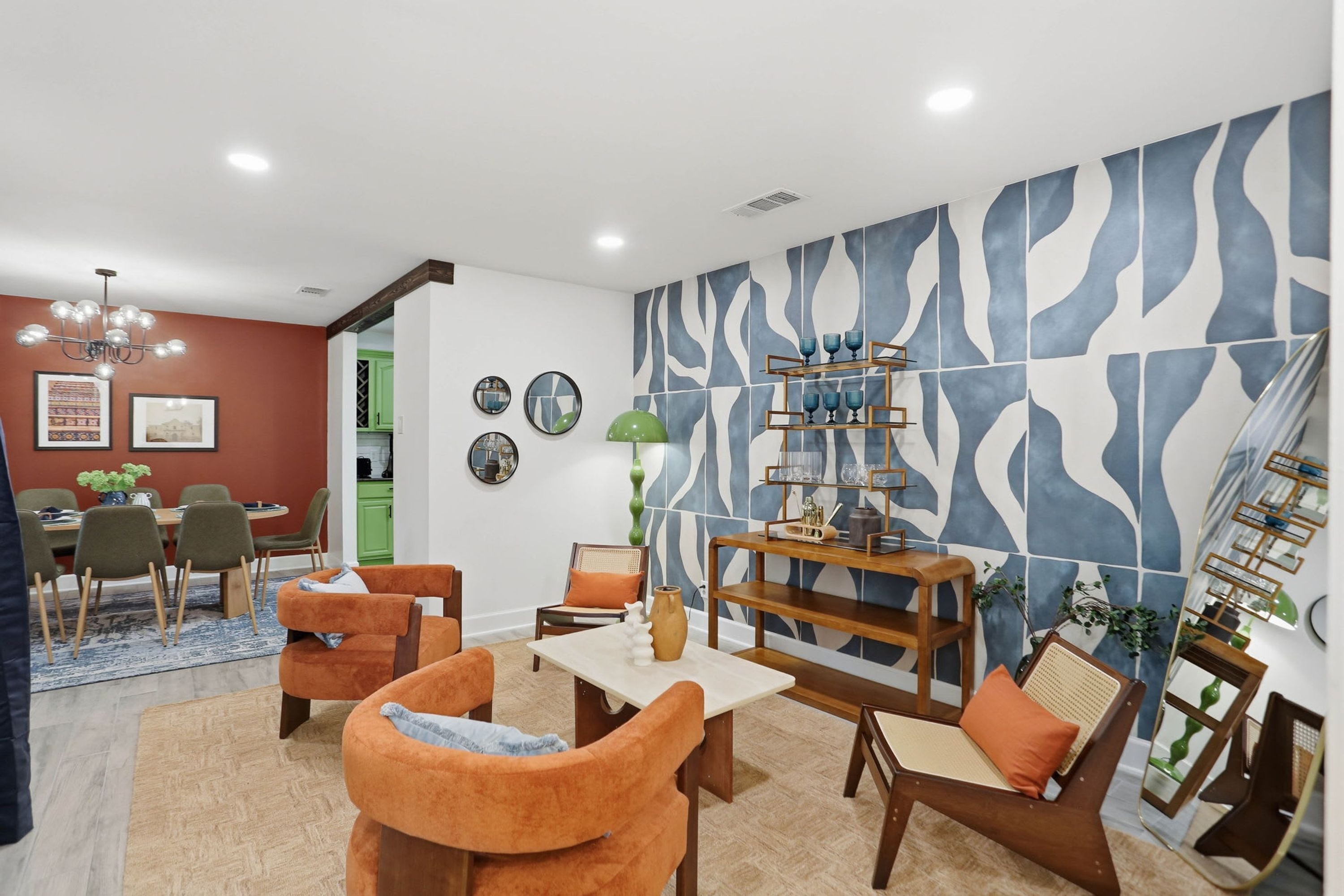 A modern living room with a dining area, featuring a unique blue and white patterned wall, a wooden coffee table, and comfortable seating.