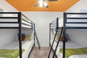 Ein Zimmer mit zwei Etagenbetten, einem Deckenventilator und einem gemusterten Teppich.