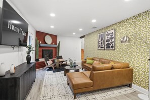 Un salon moderne avec un canapé en cuir, un téléviseur à écran plat et une cheminée.