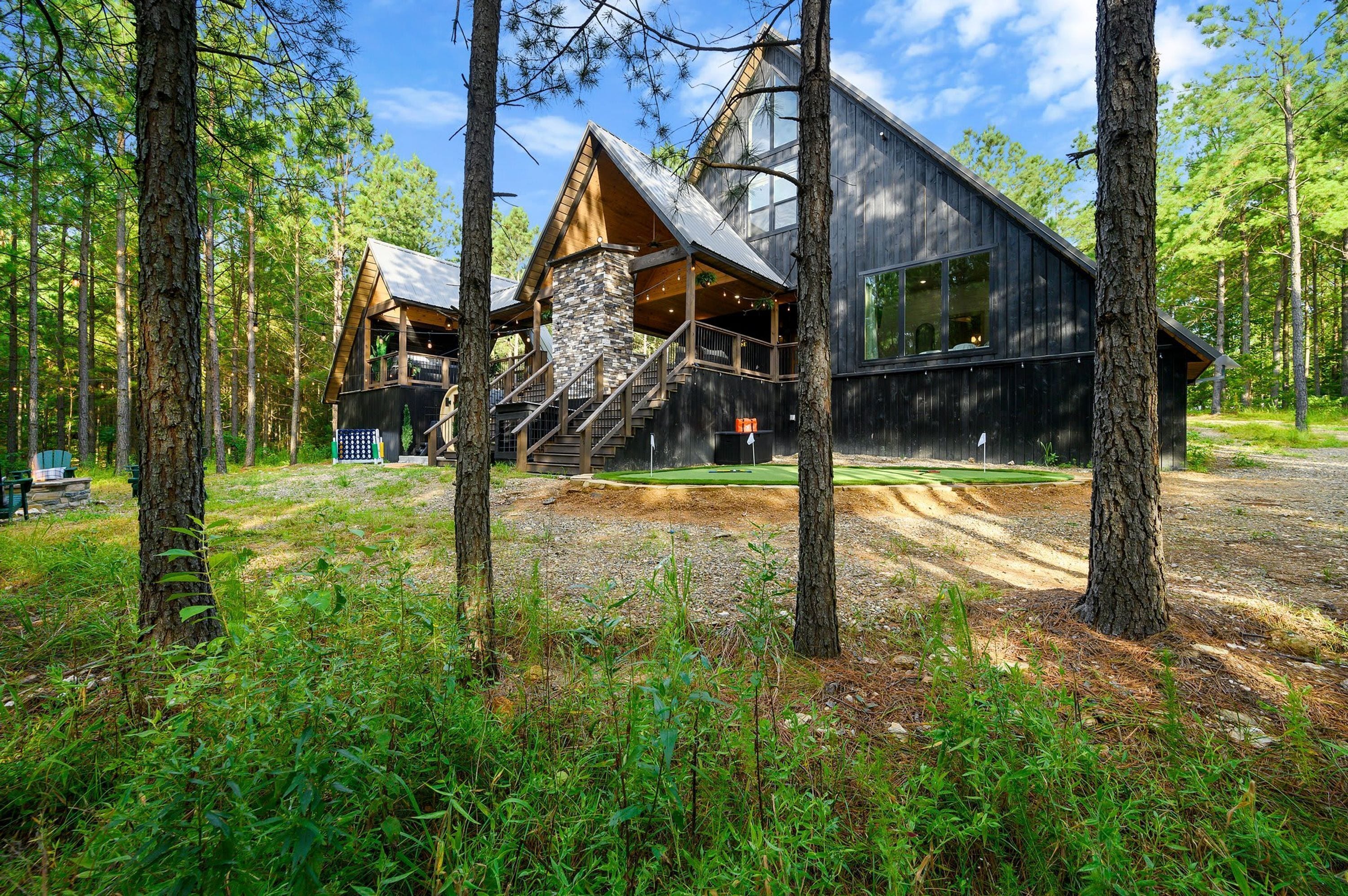 A cabin with a stone staircase, wooden deck, and a view of the surrounding forest.