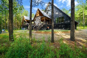 Une cabane dotée d’un escalier en pierre, d’une terrasse en bois et offrant une vue sur la forêt environnante.