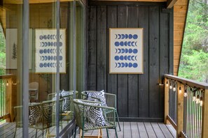 Terraza de madera con mobiliario exterior y cuadros enmarcados que representan las fases de la luna.