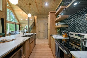 Una cocina moderna con armarios de madera, encimera de mármol y salpicadero de baldosas negras.