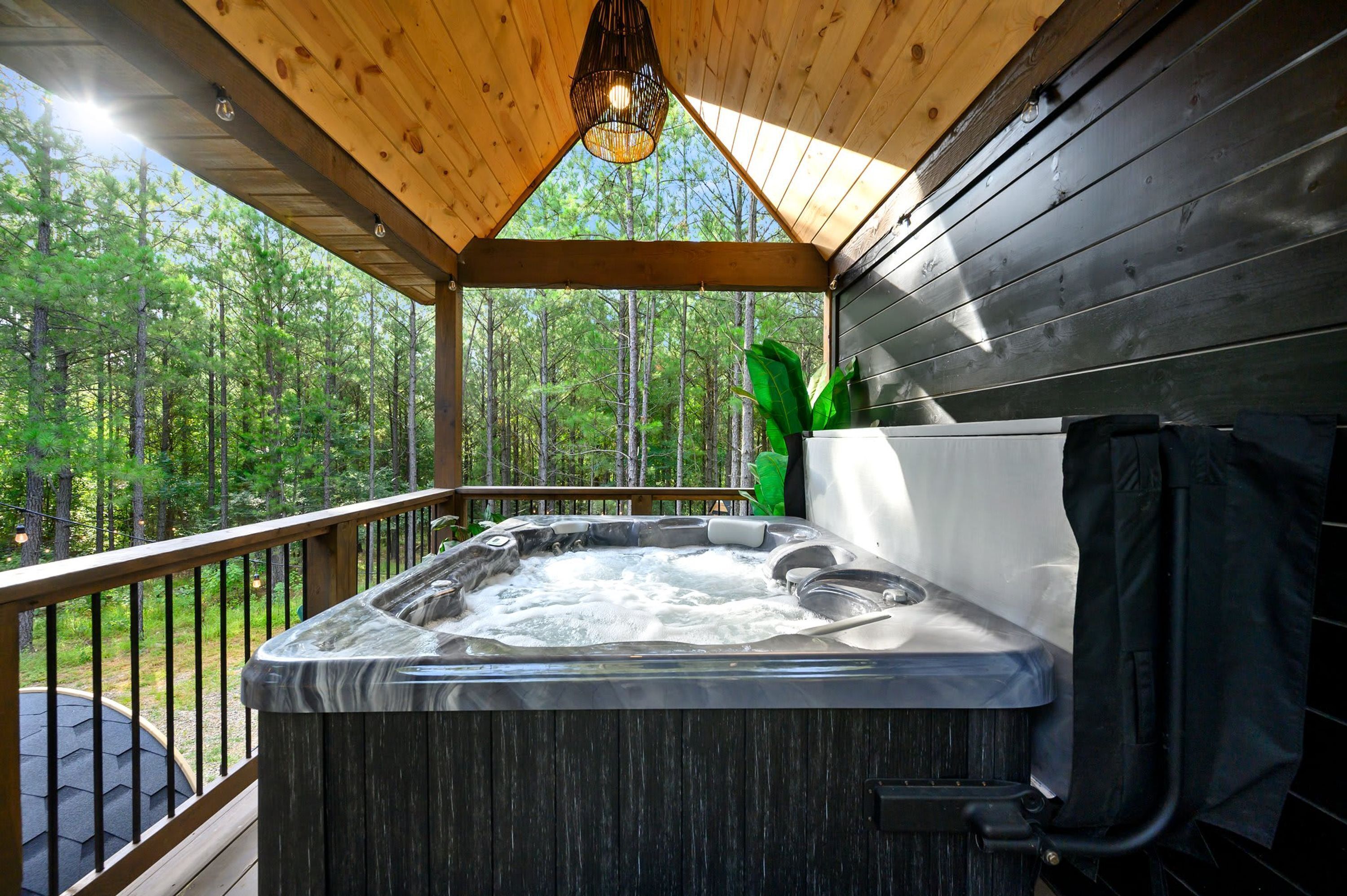 A hot tub on a wooden deck with a view of a forest.