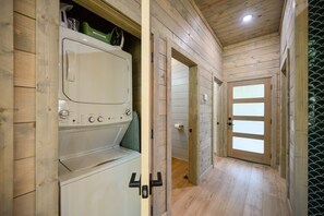 Un cuarto de lavado con lavadora y secadora, paredes de madera y piso de baldosas.