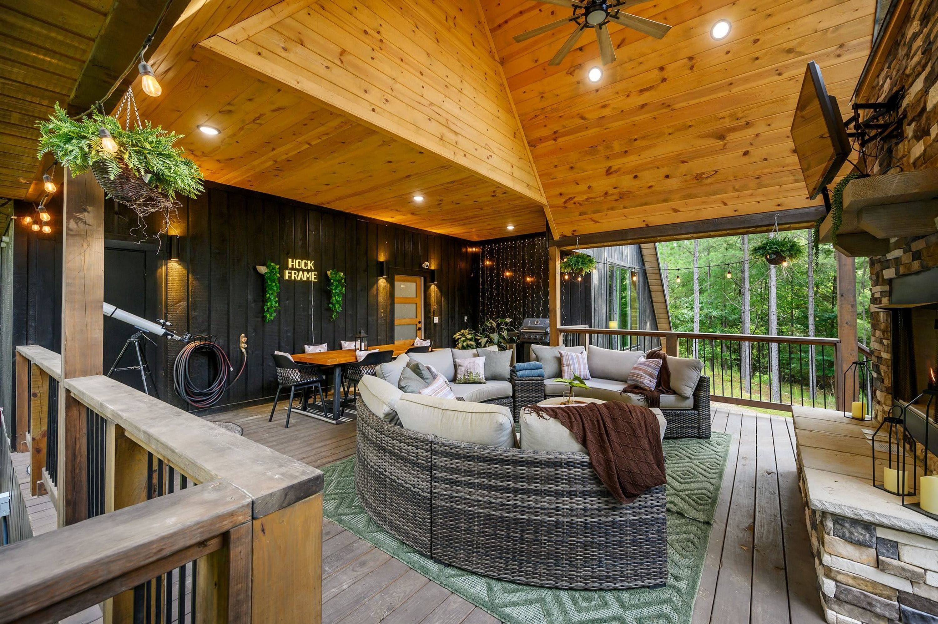 A cozy cabin interior with a wooden ceiling, a fireplace, and a seating area with a sofa and a dining table.