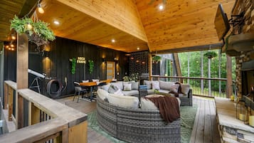 A cozy cabin interior with a wooden ceiling, a fireplace, and a seating area with a sofa and a dining table.