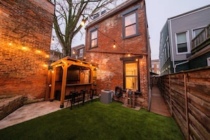 A brick building with a wooden deck and outdoor seating area. - Velvet Haus Downtown 3rd Floor Deck Backyard (Cincinnati)