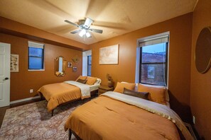 A bedroom with two beds, a ceiling fan, and a large window. - Velvet Haus Downtown 3rd Floor Deck Backyard (Cincinnati)
