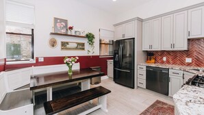 A modern kitchen with white cabinetry, a stainless steel refrigerator, and a herringbone-patterned backsplash. - Velvet Haus Downtown 3rd Floor Deck Backyard (Cincinnati)