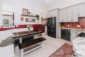 Eine moderne Küche mit weißen Schränken, einem Edelstahlkühlschrank und einer Fischgrätenmuster-Spritzschutzleiste.