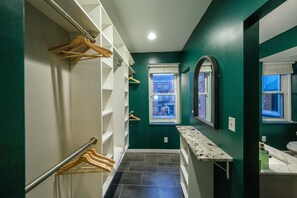 A narrow hallway with a built-in closet, a bench, and a window with a view of a building. - Velvet Haus Downtown 3rd Floor Deck Backyard (Cincinnati)