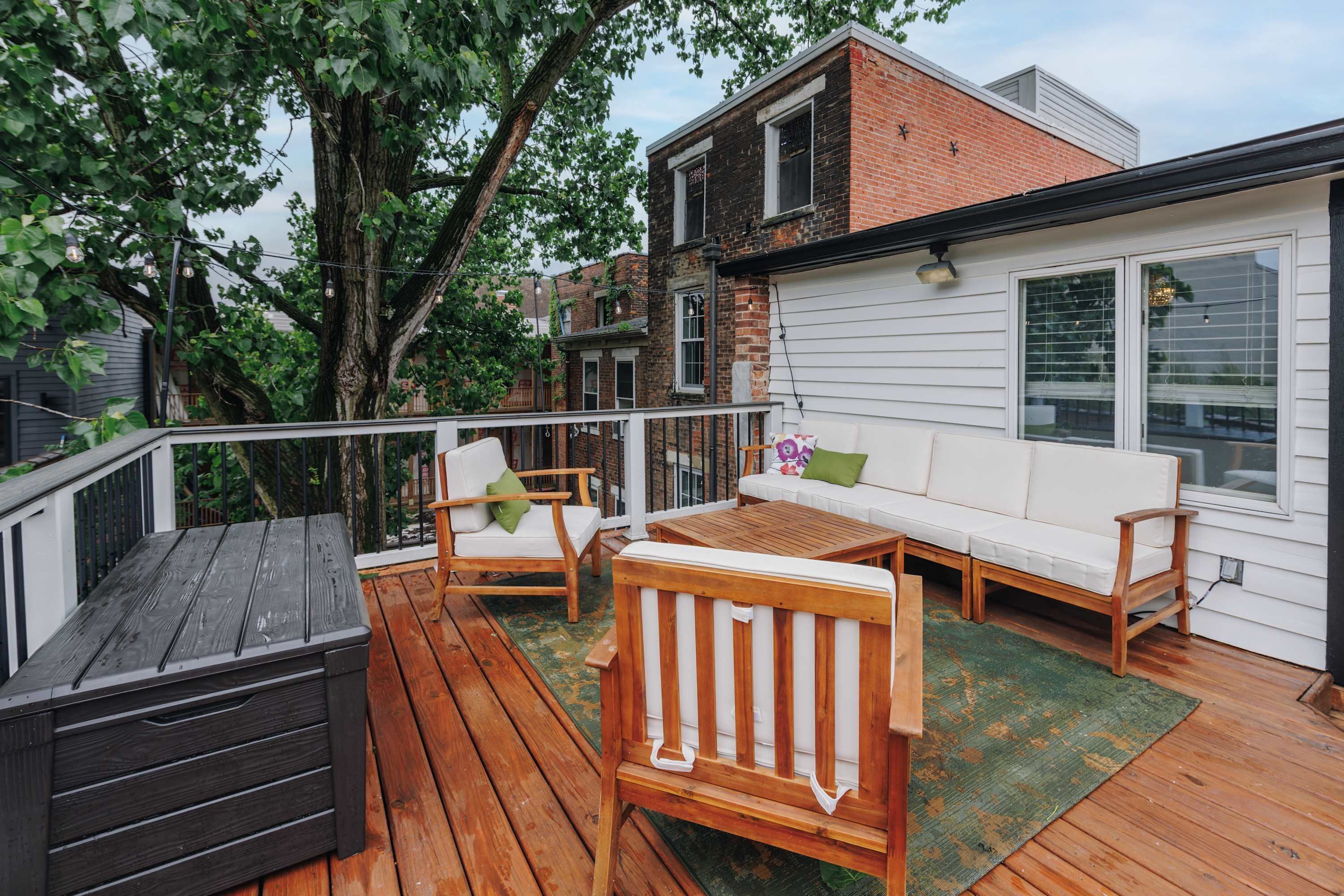 A deck with a wooden table, two chairs, and a sofa.