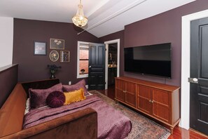 Ein Schlafzimmer mit einem Bett, einem Fernseher, einem Kleiderschrank und einer Tür zu einem anderen Raum.