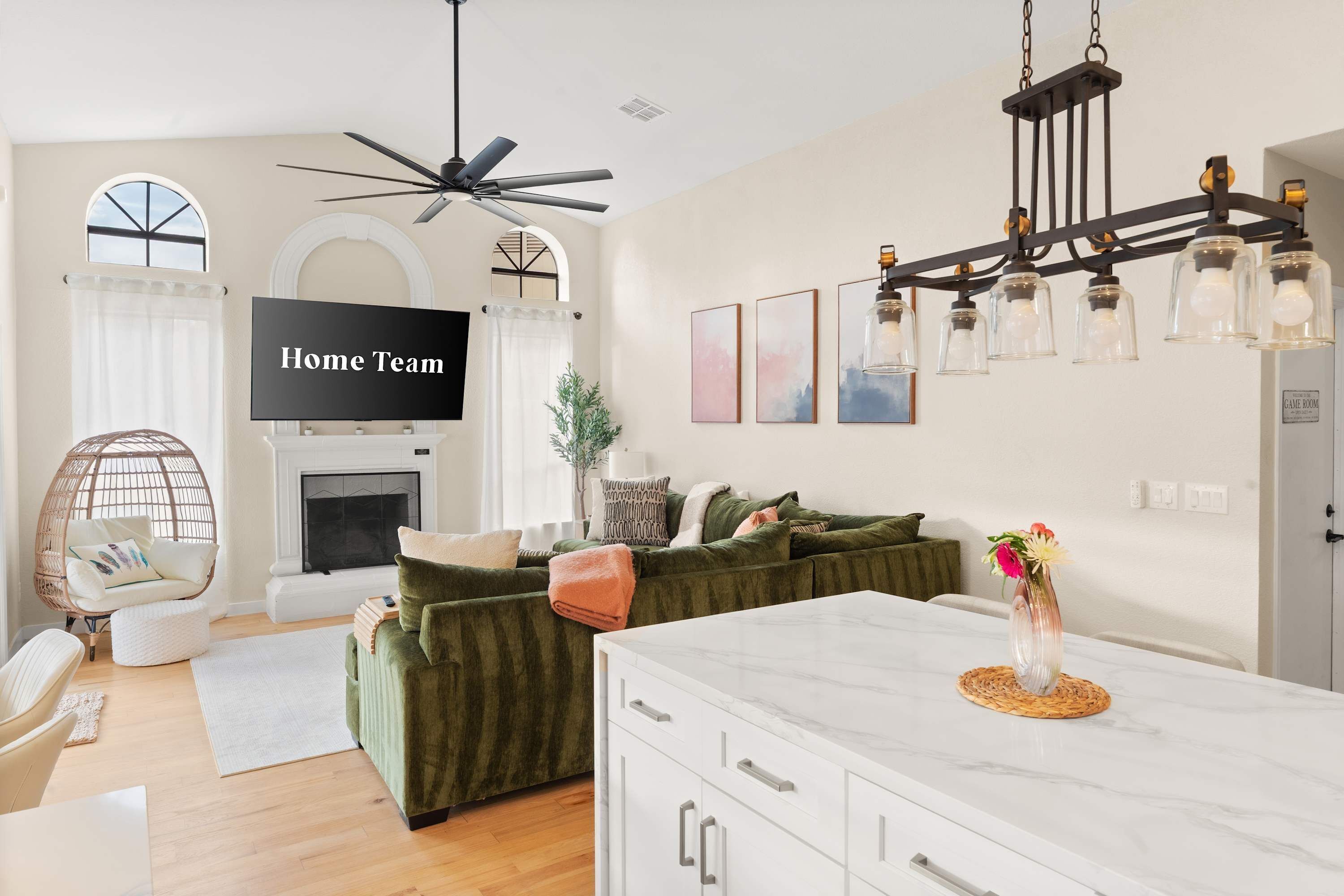A modern living room with a green sofa, a white coffee table, a fireplace, and a ceiling fan.