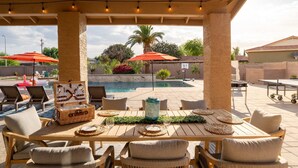An outdoor patio with a pool, lounge chairs, and a dining table set for two. - The Ultimate Stay Play Retreat 4BR Sleeps 13 (Chandler)