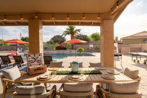 An outdoor patio with a pool, lounge chairs, and a dining table set for two. - The Ultimate Stay Play Retreat 4BR Sleeps 13 (Chandler)