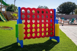 A children's play area with a large red and blue play structure, artificial grass, and a slide. - The Ultimate Stay Play Retreat 4BR Sleeps 13 (Chandler)