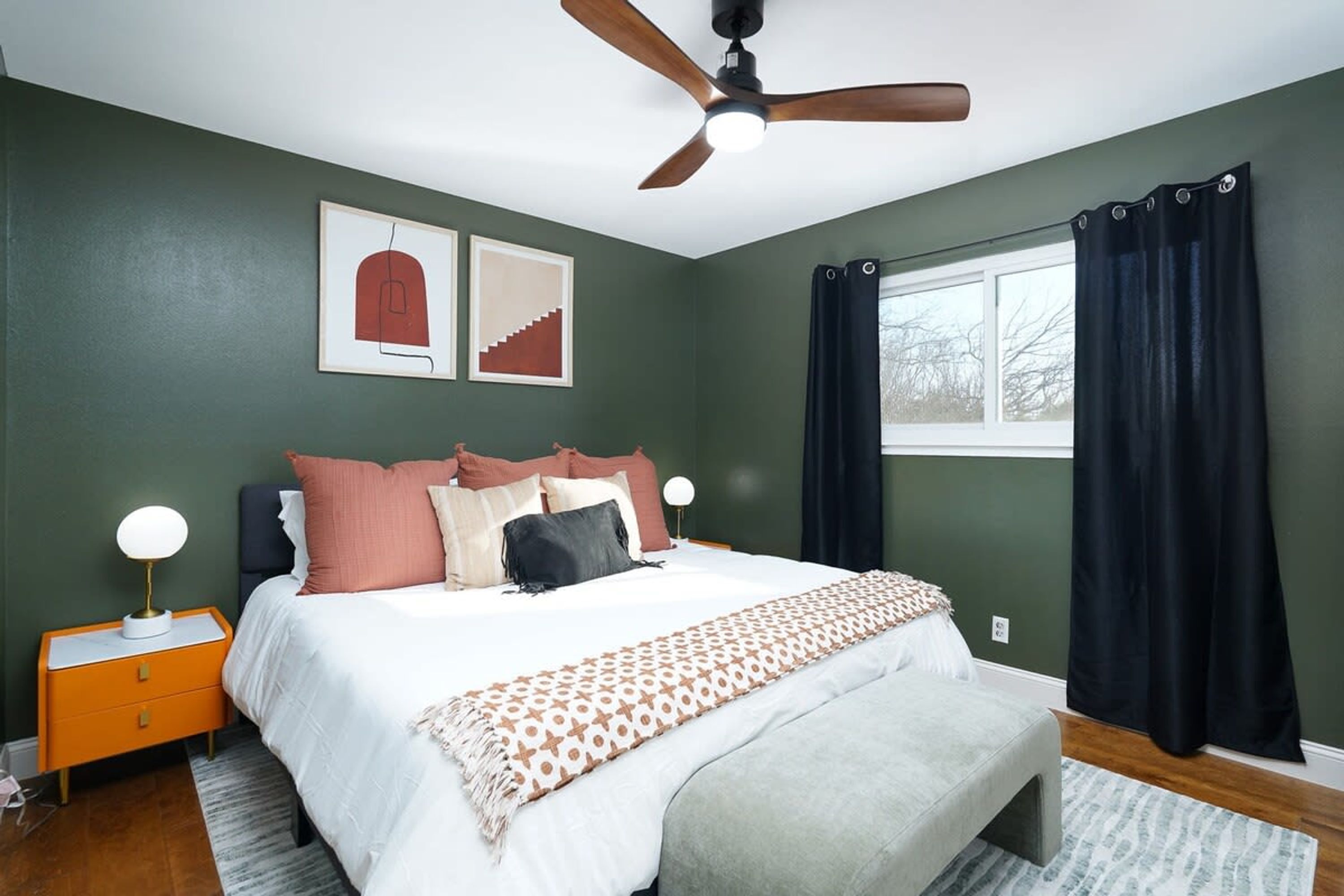 A bedroom with a bed, nightstands, a ceiling fan, and a window with curtains.