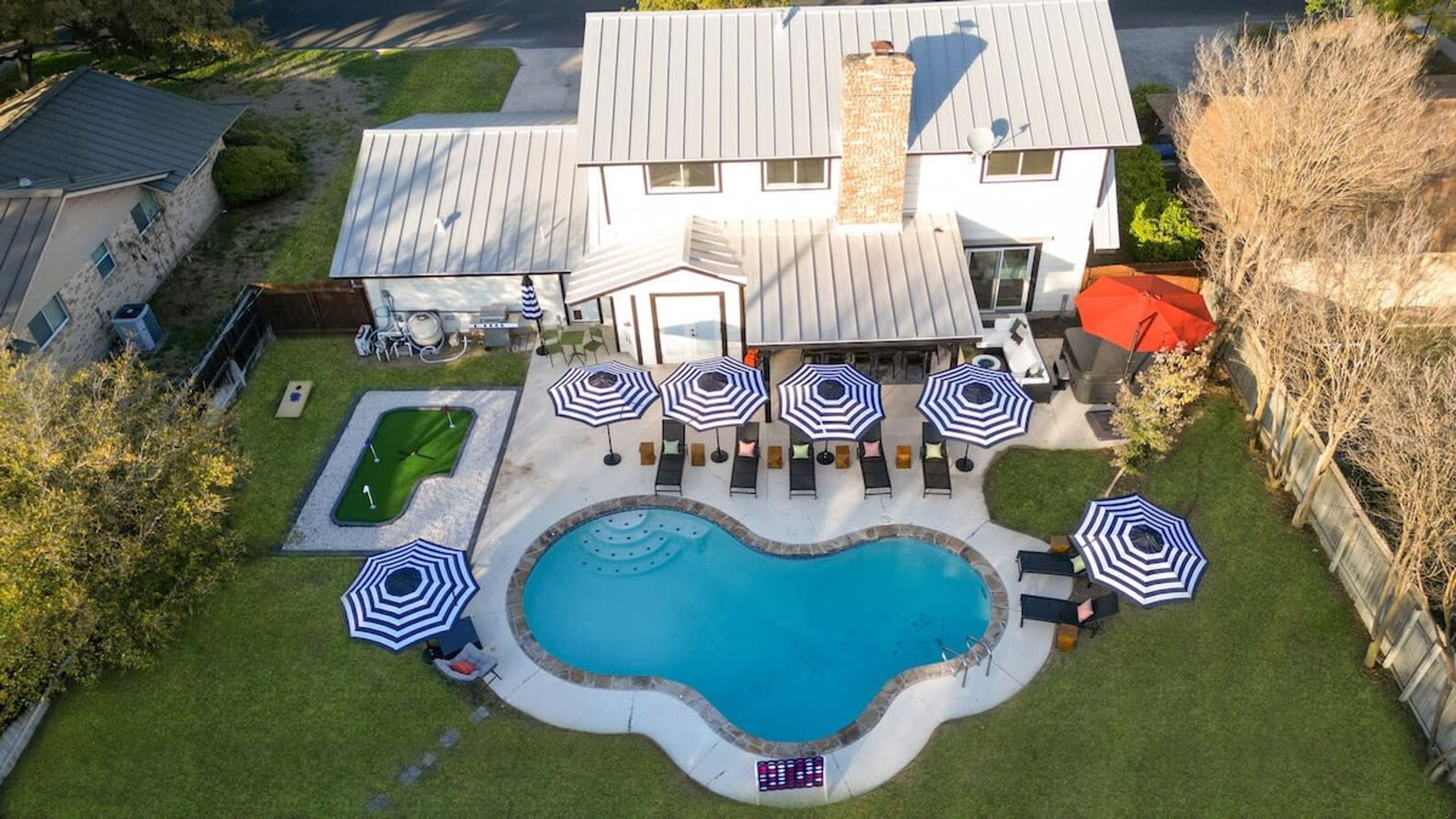 A residential property with a swimming pool, outdoor seating, and a well-maintained lawn.