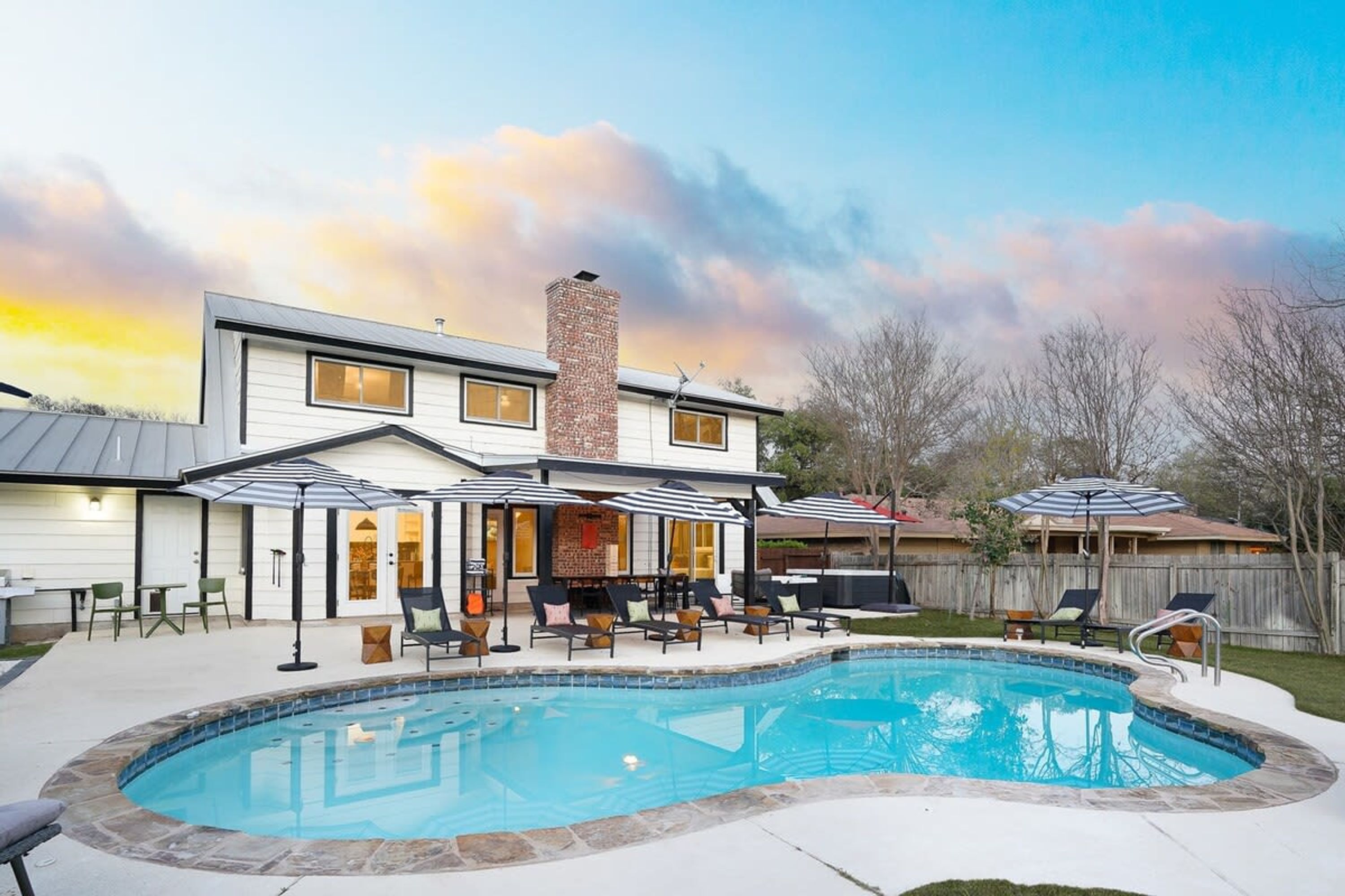 A modern two-story house with a swimming pool, outdoor seating, and a brick chimney.