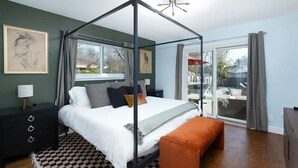 A bedroom with a four-poster bed, a checkered rug, and a view of the outdoors. - Texas Tranquility Hot Tub Pool Putt Putt More (San Antonio)