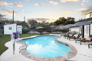 Ein Garten mit Swimmingpool, Liegestühlen und einem kleinen Gartenhaus.