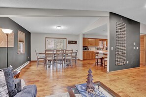 Ein modernes Wohnzimmer mit Essbereich, Holzboden und einer Küche im Hintergrund.