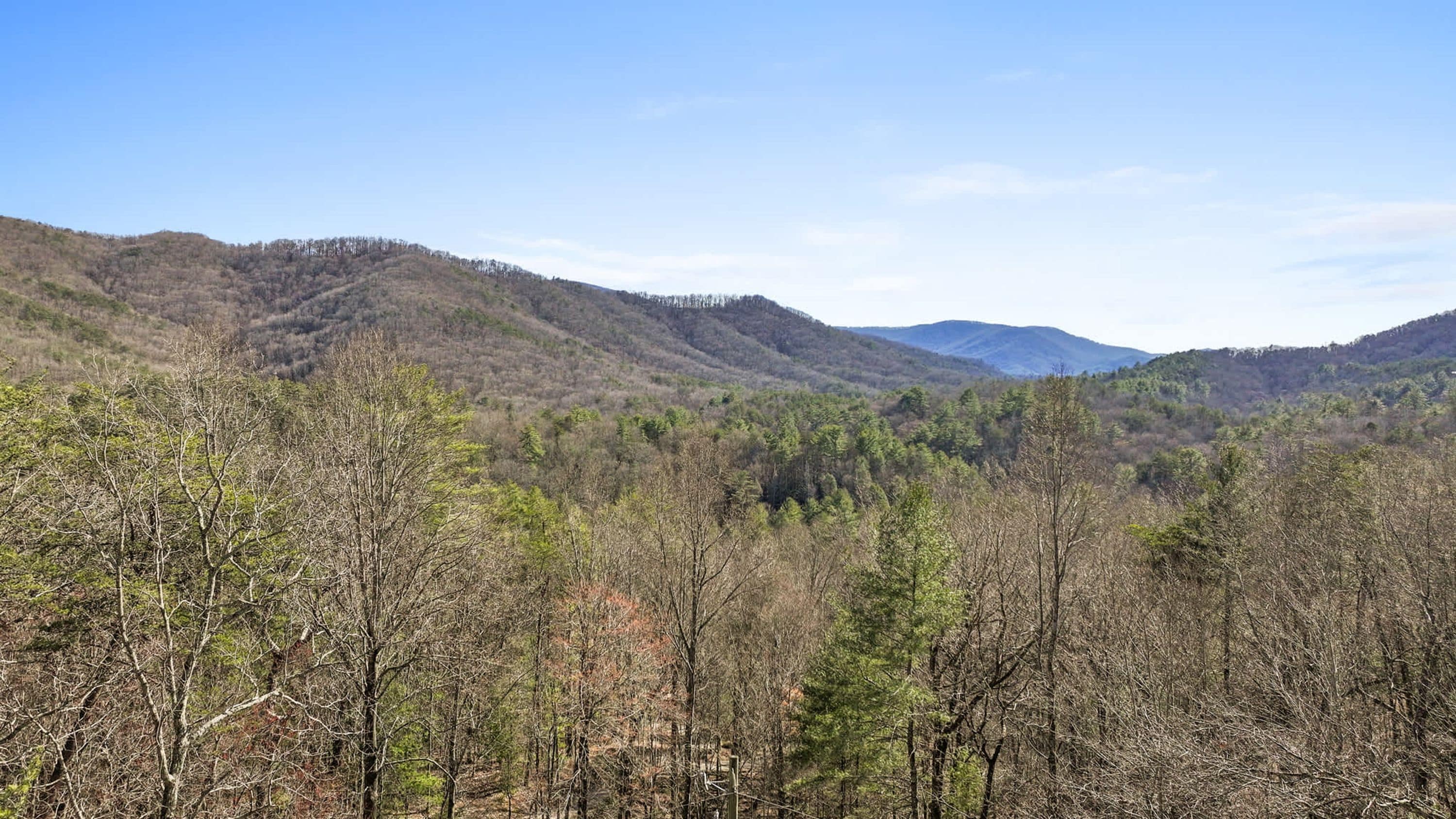 A mountainous landscape with dense forests and a clear sky.